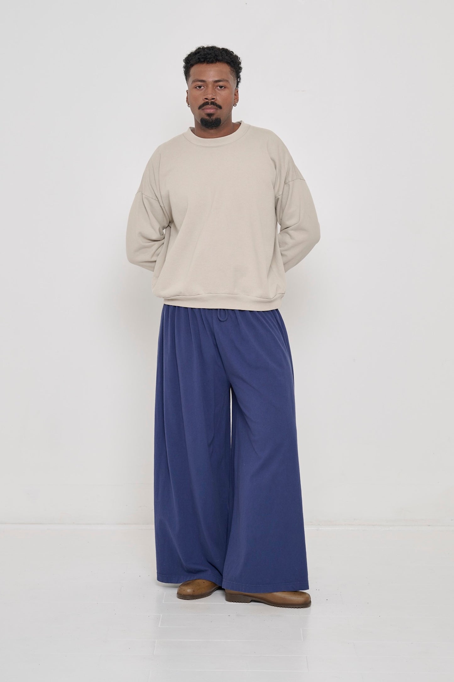Man wearing Oat Trash Crewneck and Washed Navy Tubular Pants. 