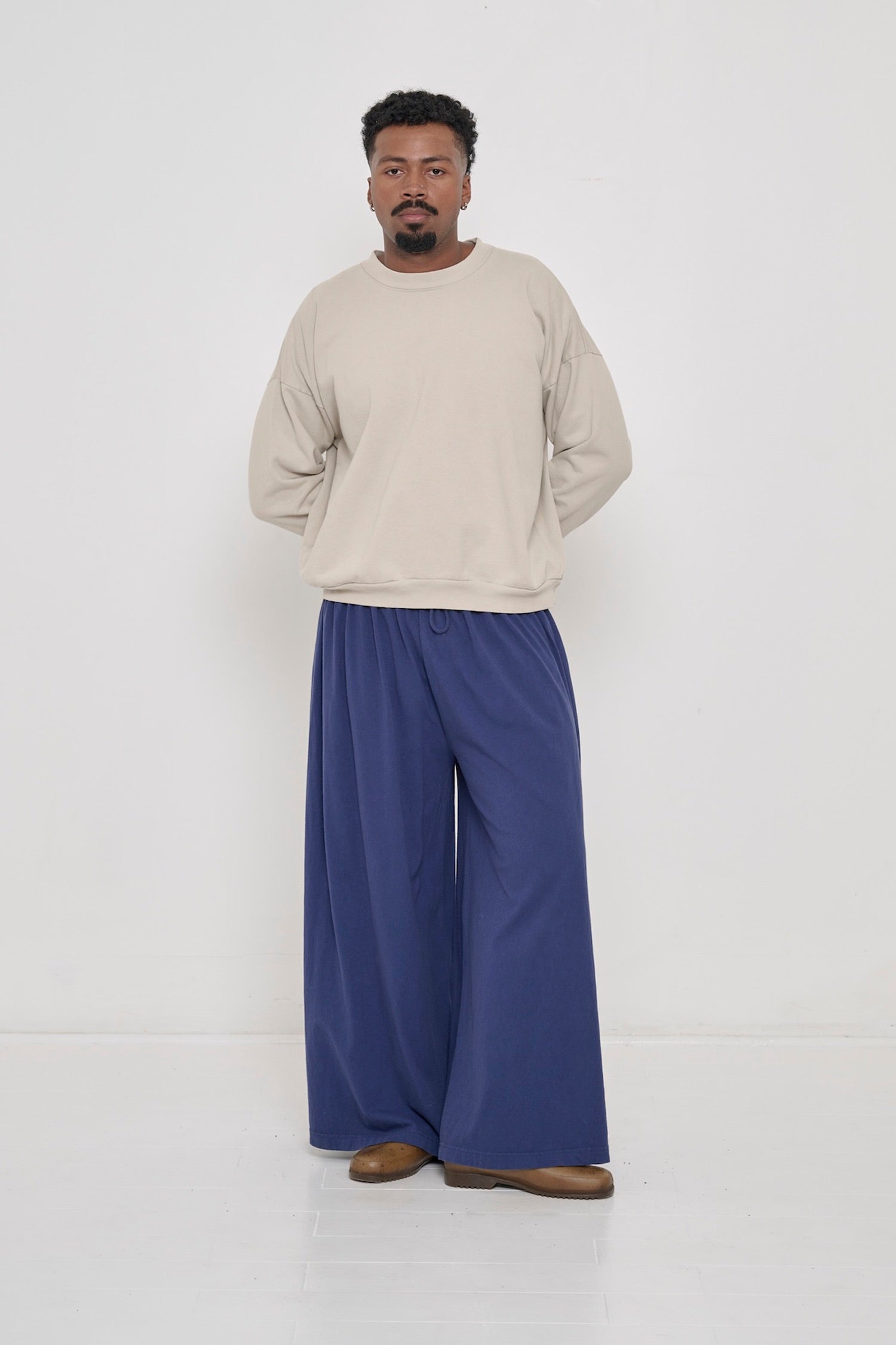 Man wearing Oat Trash Crewneck and Washed Navy Tubular Pants. 
