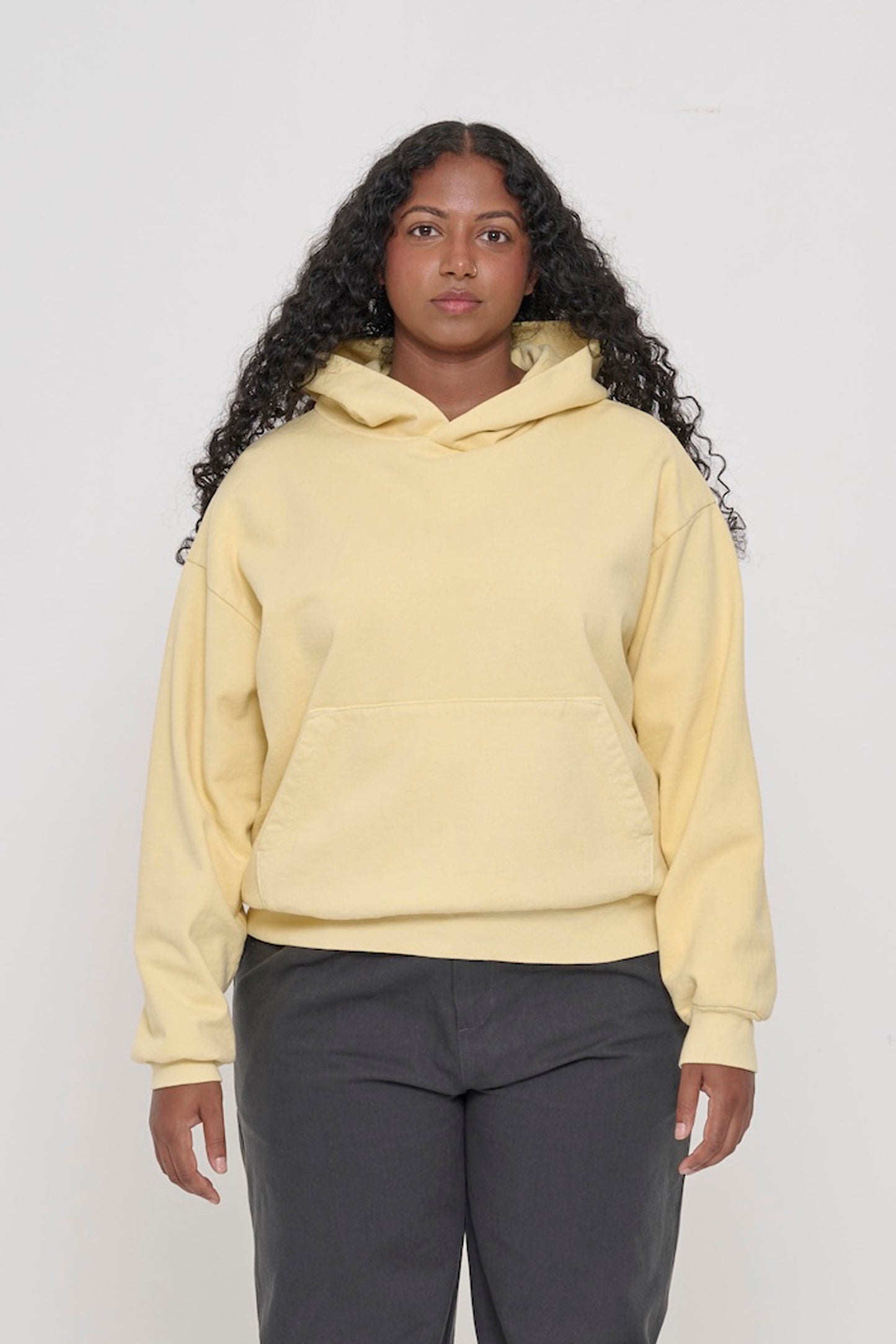 Front view of a woman wearing a French Butter Trash Hoodie. Hem hits her hip.