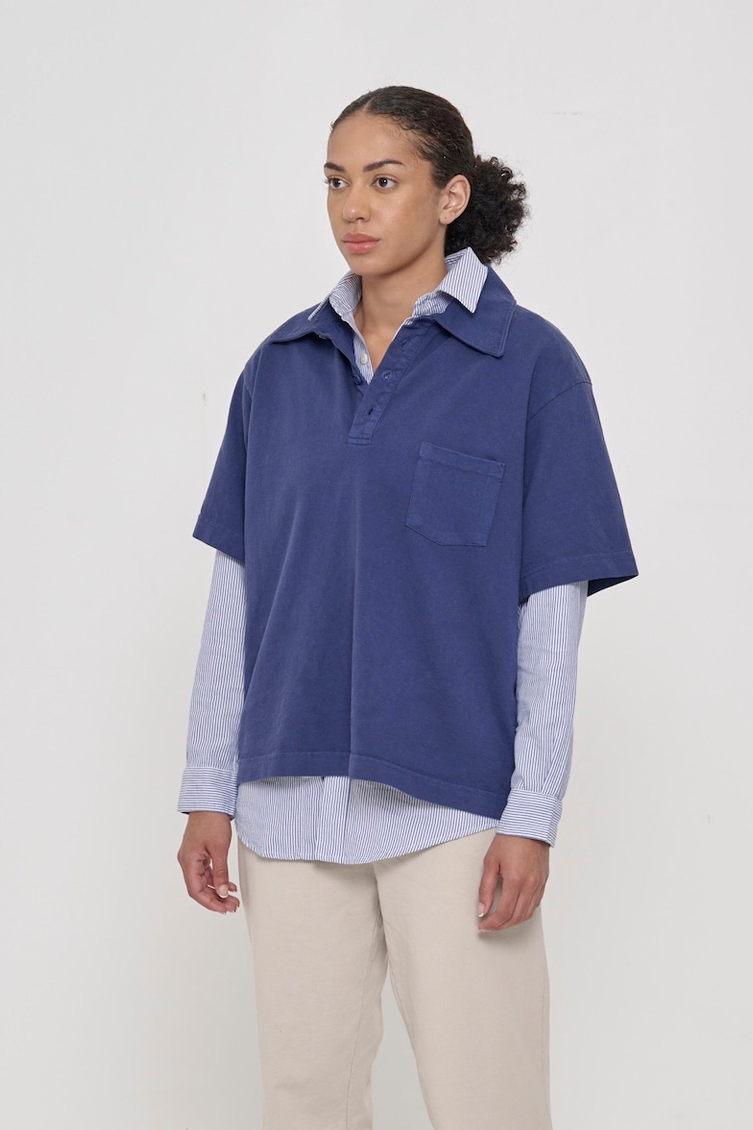 Woman turned 45 degrees, wearing a Washed Navy Trash Polo, showing relaxed boxy body and sleeves.
