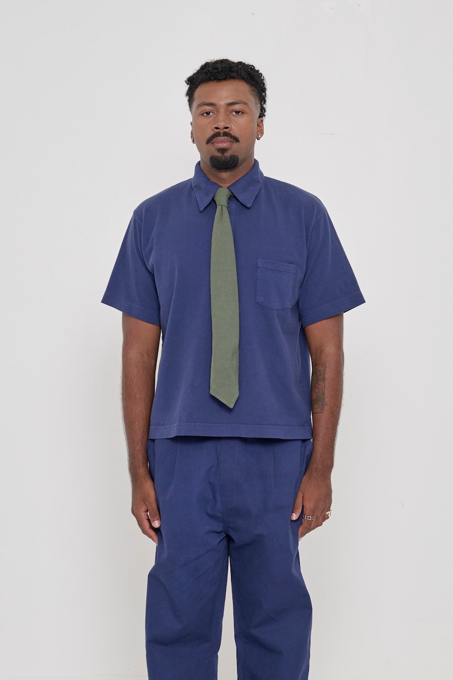 Front view of a 6'2" man wearing a Trash Polo in Washed Navy with a Trash Tie in Pine. 