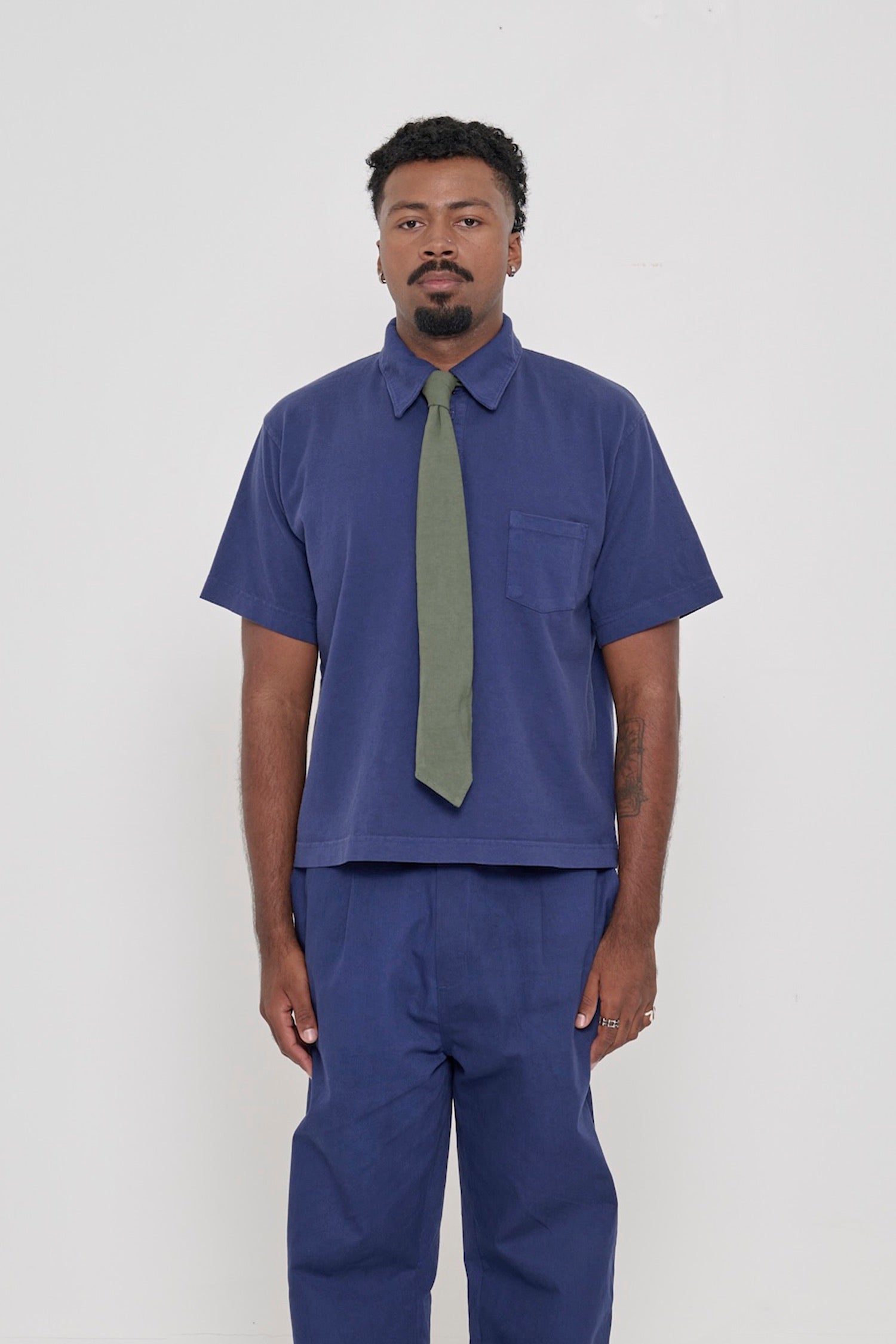 Front view of a 6'2" man wearing a Trash Polo in Washed Navy with a Trash Tie in Pine. 