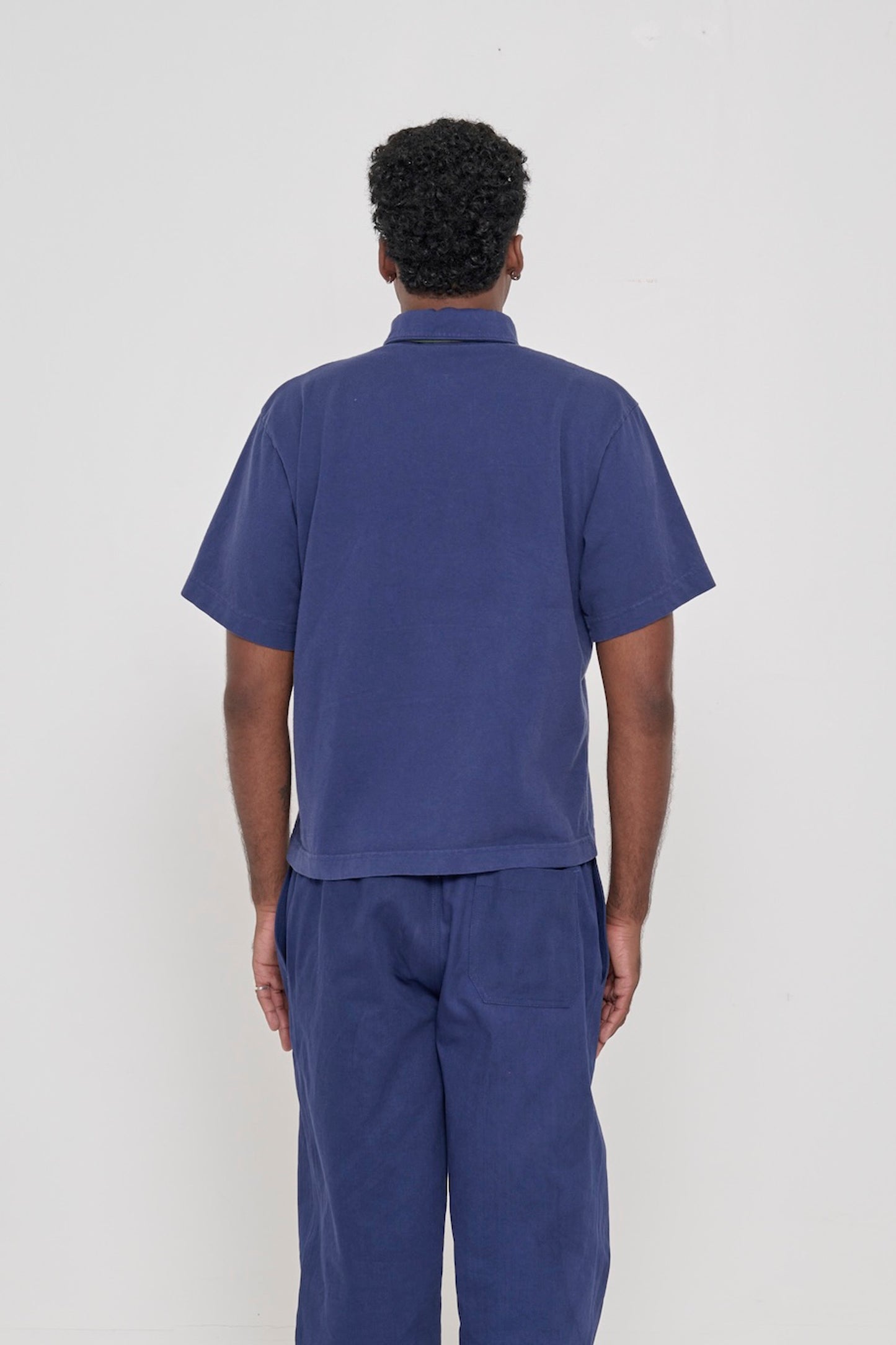 Washed Navy Trash Polo, back view on a person. Roomy and boxy fit throughout.