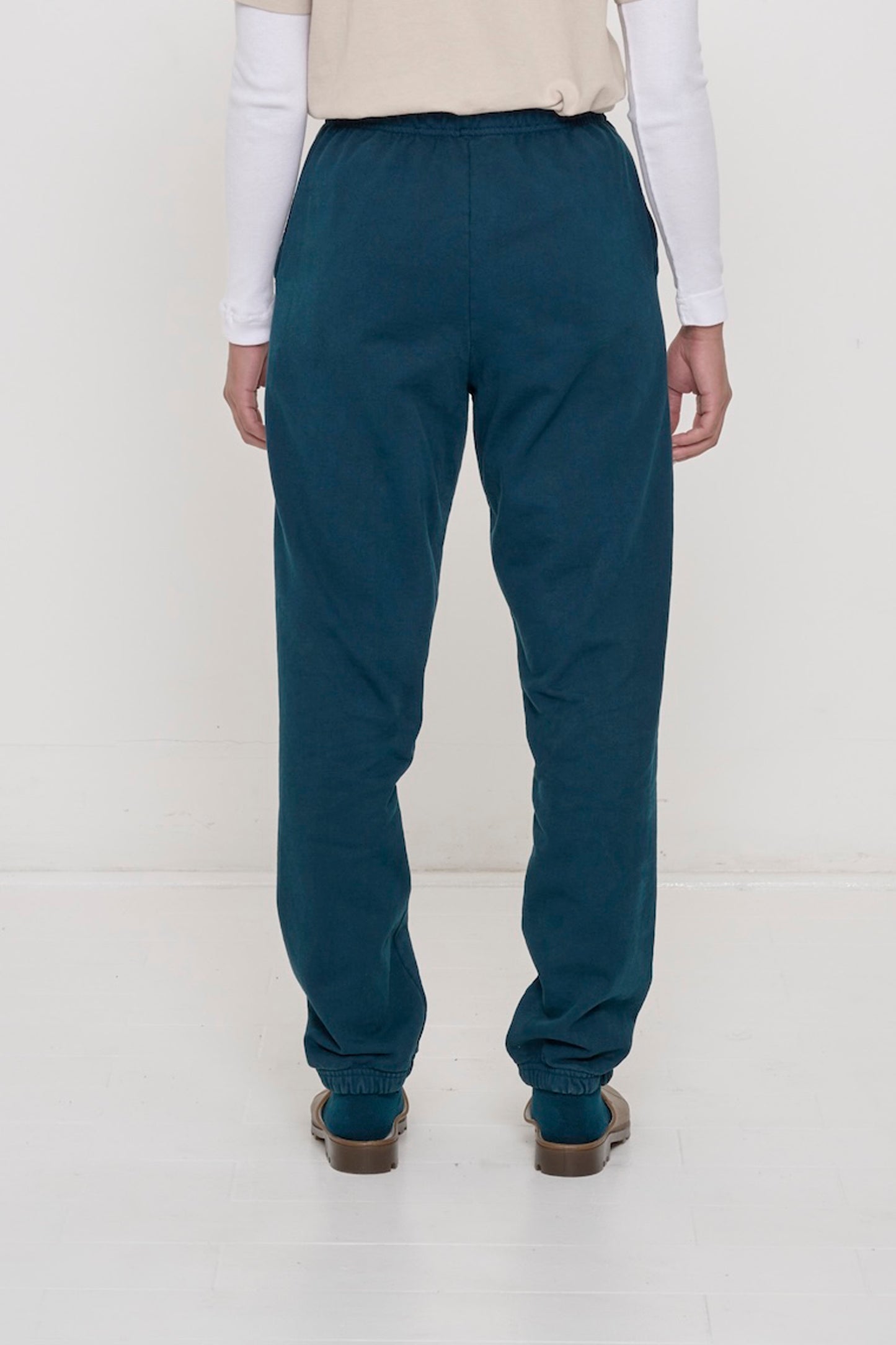 Back view of a person wearing Juniper Trash Sweatpants, relaxed fit throughout, except for elastic waistband and cuffs.