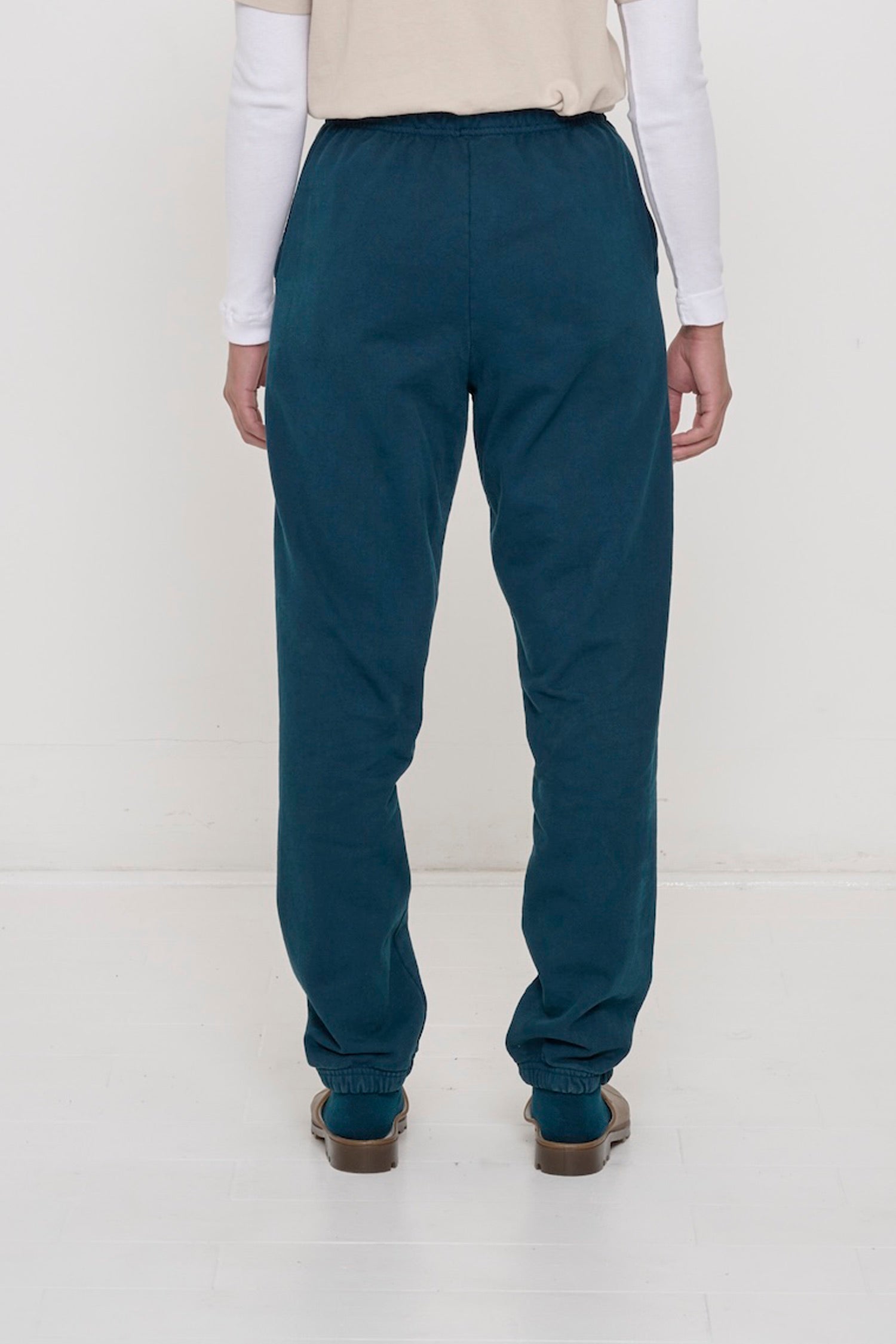 Back view of a person wearing Juniper Trash Sweatpants, relaxed fit throughout, except for elastic waistband and cuffs.