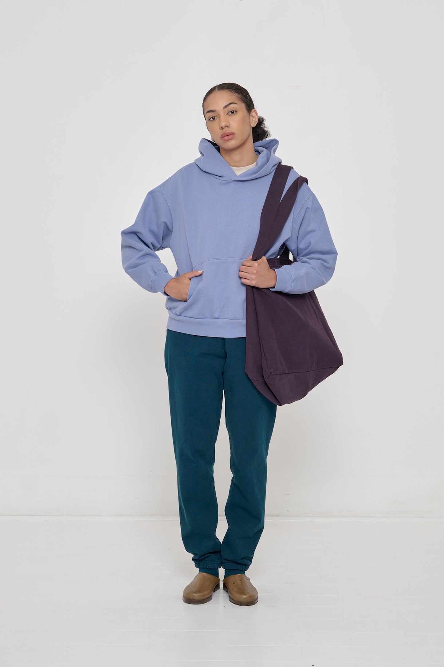Person wearing Periwinkle Trash Hoodie with hands in pockets and Juniper Trash Sweatpants.