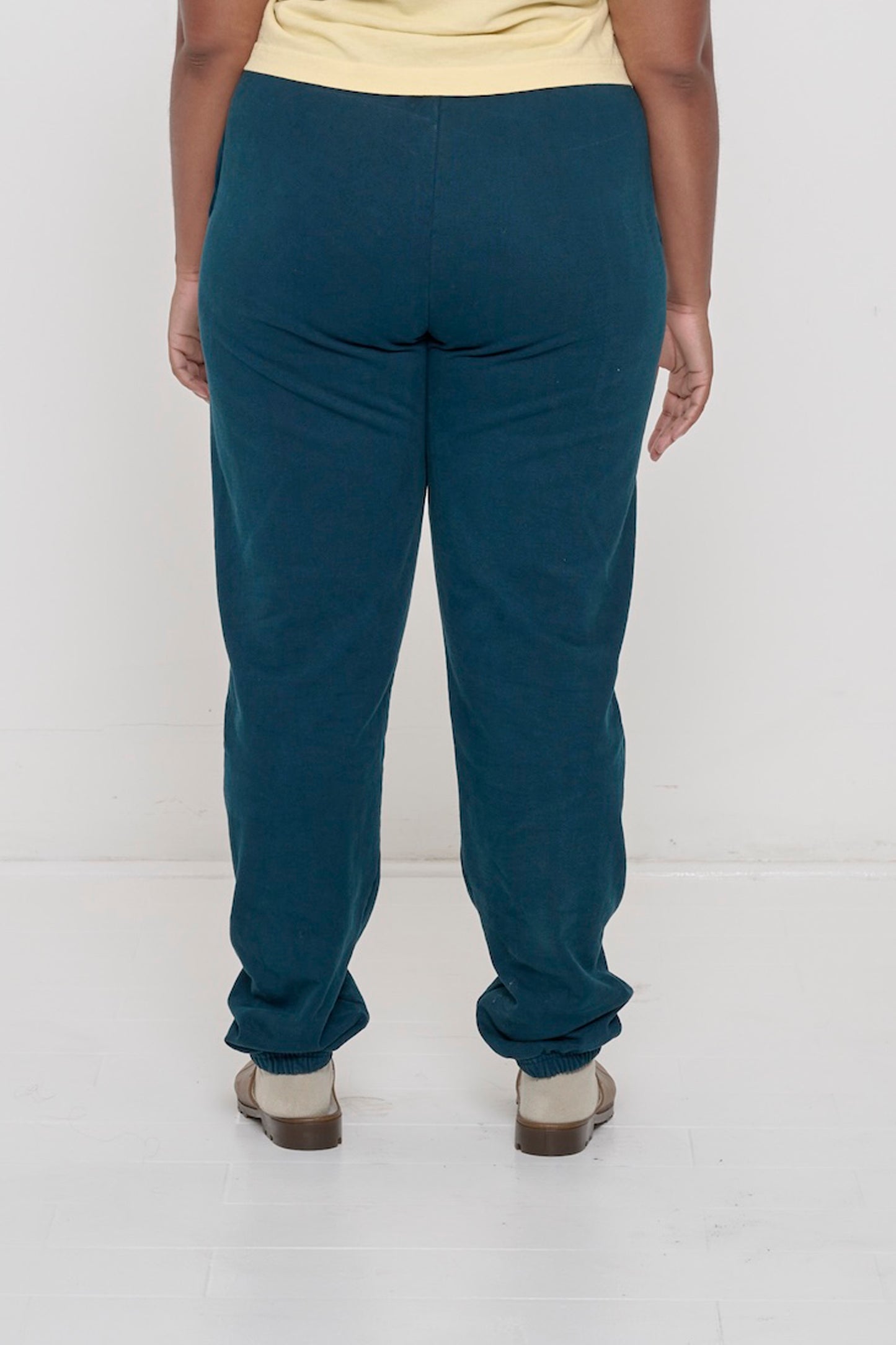 Back view of a person wearing Juniper Trash Sweatpants, relaxed fit throughout, except for elastic waistband and cuffs.