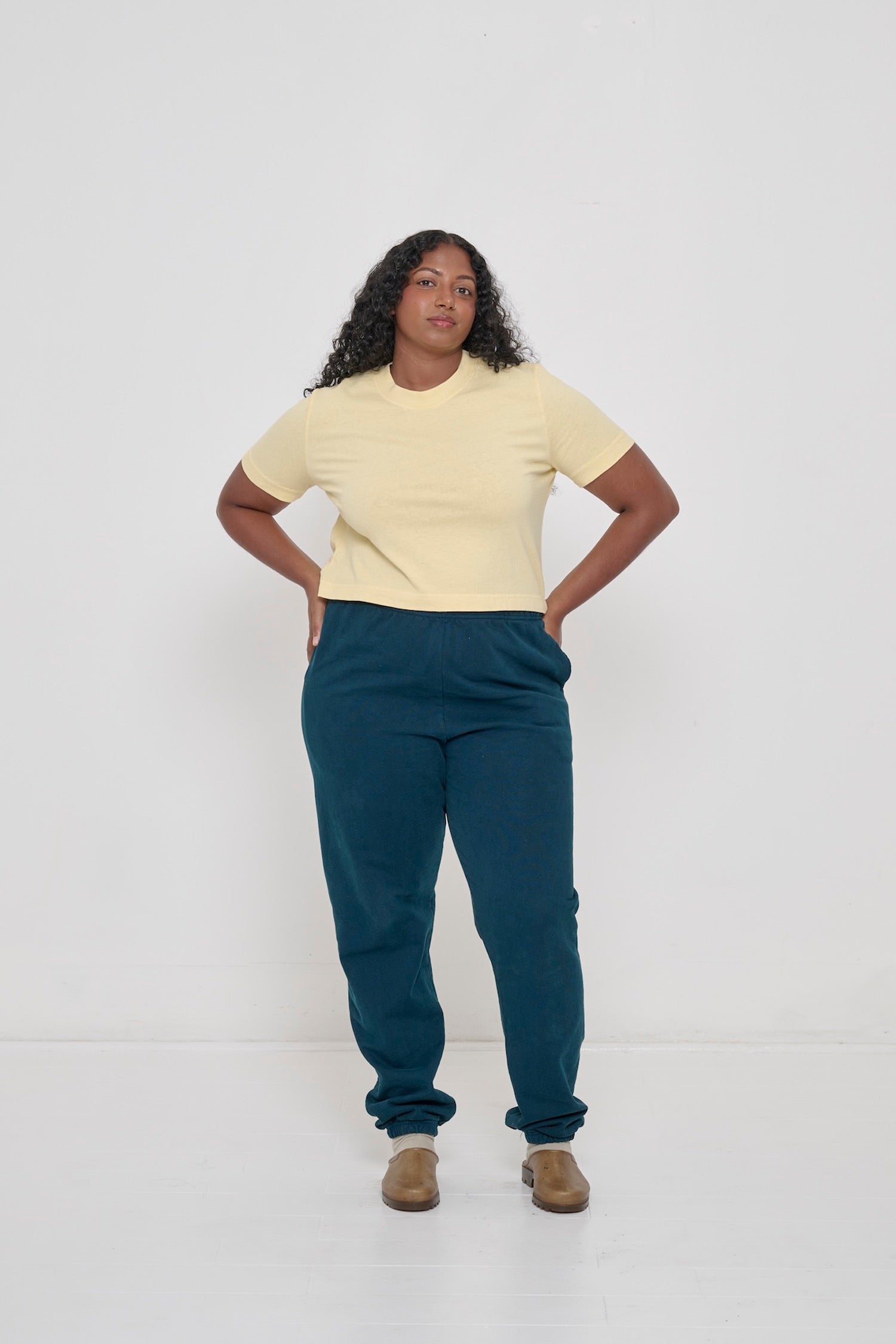 Person wearing French Butter Baby Trash Tee with hands on hips of Juniper Trash Sweatpants.