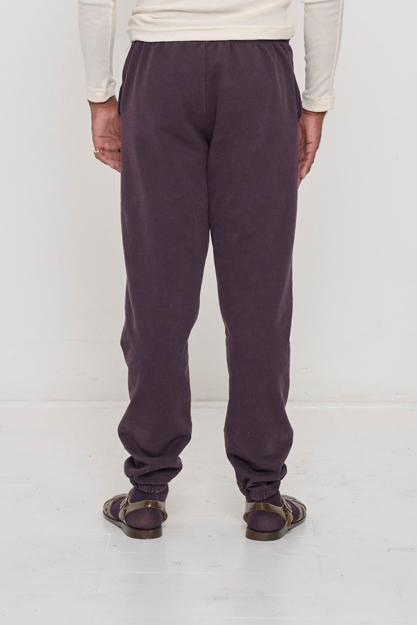 Back view of a person wearing Mulberry Trash Sweatpants, relaxed fit throughout, except for elastic waistband and cuffs.