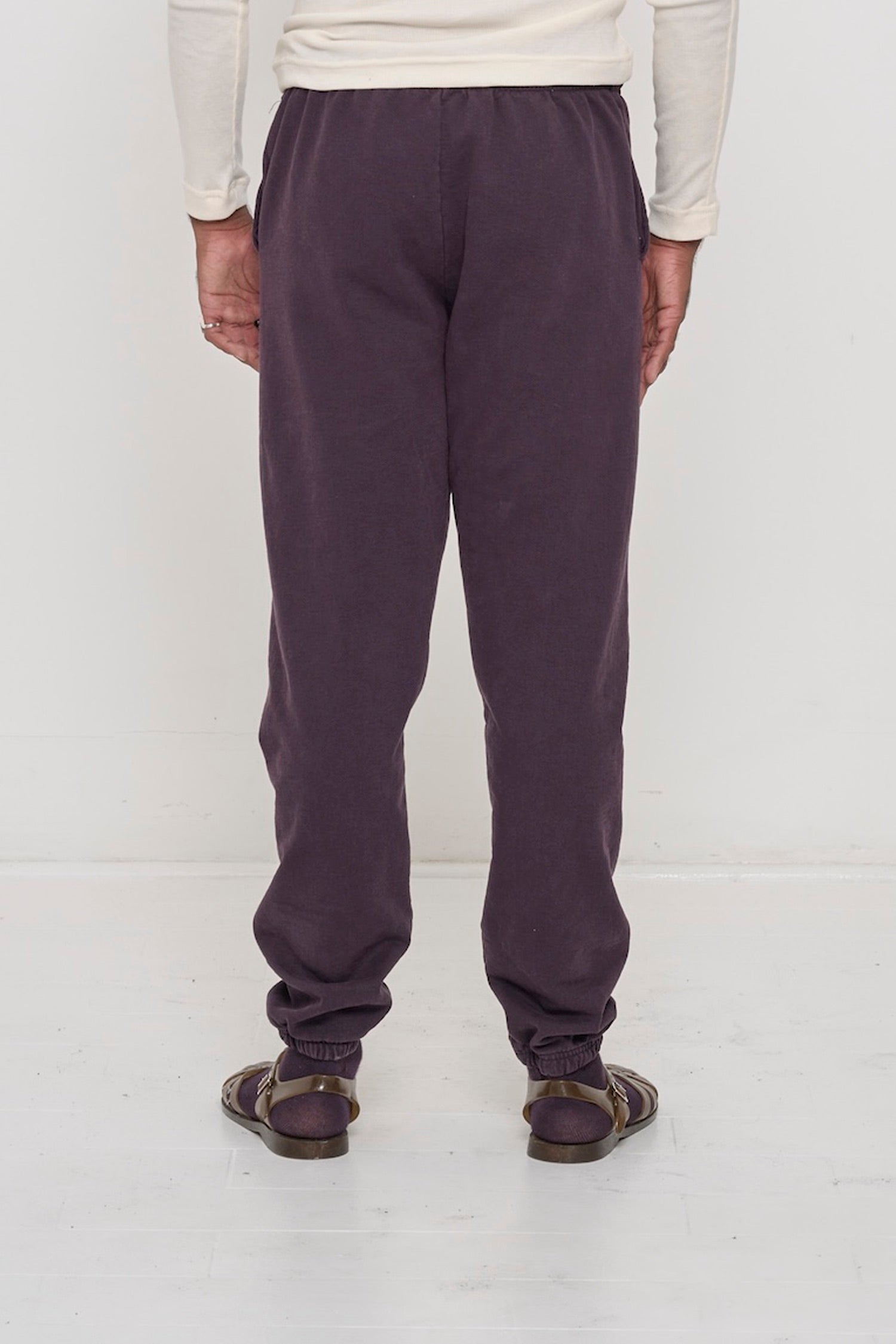 Back view of a person wearing Mulberry Trash Sweatpants, relaxed fit throughout, except for elastic waistband and cuffs.
