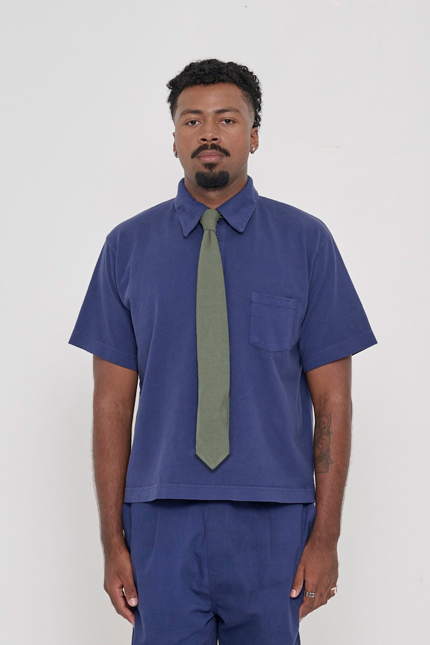 Front view of a person wearing a Pine Trash Tie with a Washed Navy Trash Polo. 