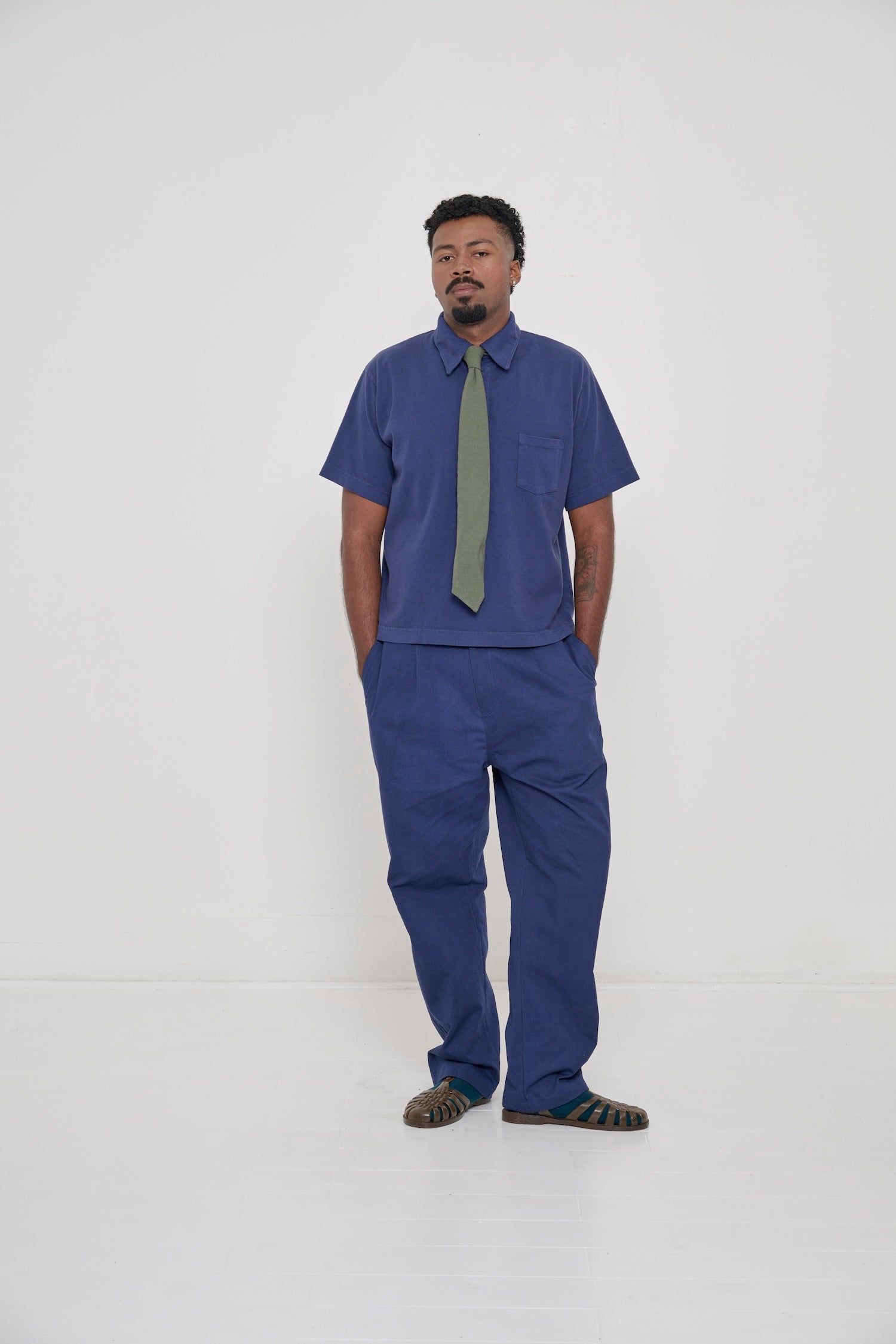 Person wearing Washed Navy Trash Polo and Life Uniform Pants with Pine Trash Tie.