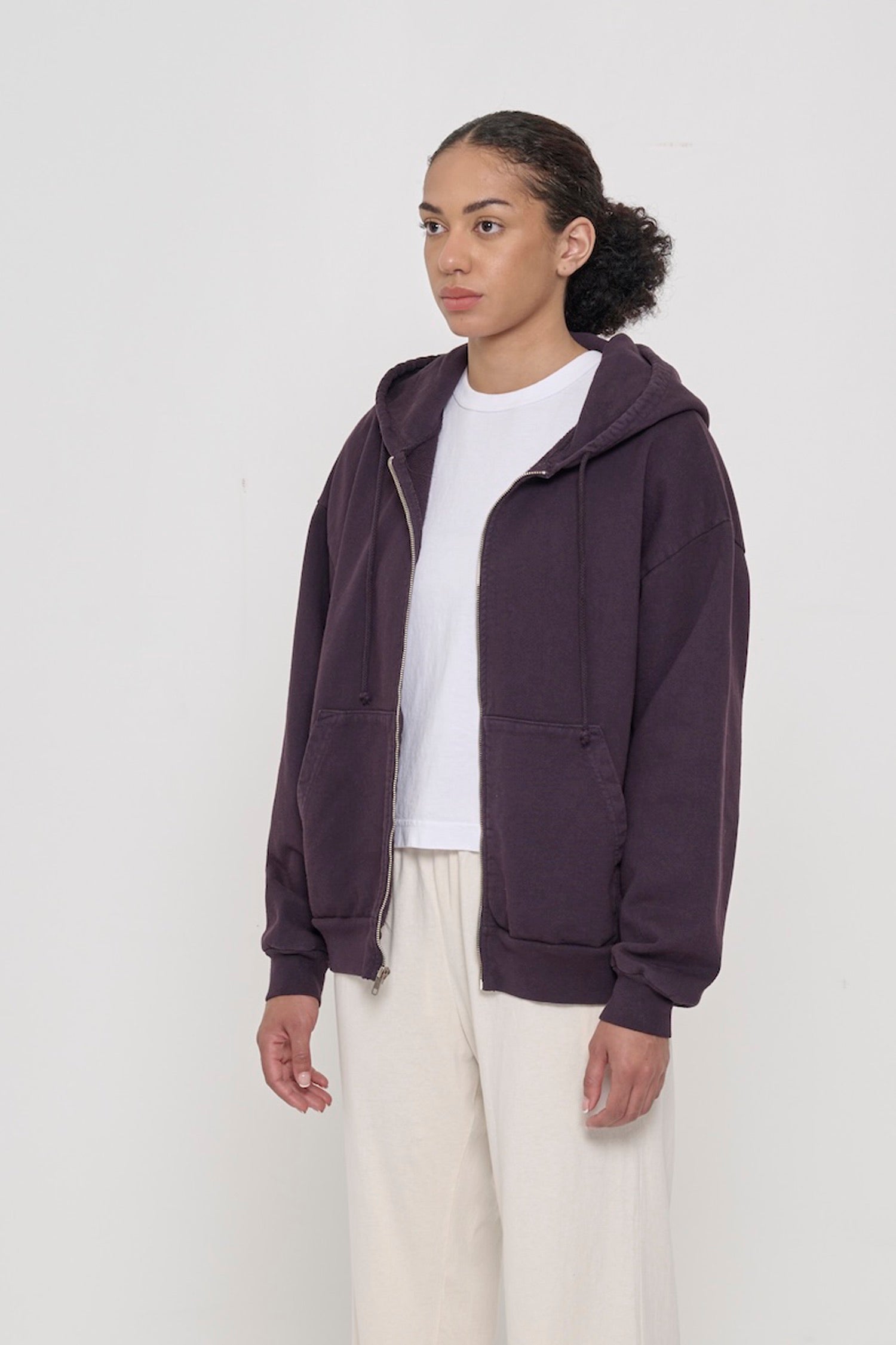 Person facing 45-degrees, wearing a Mulberry Trash Zip Up Hoodie, showcasing sleeve's relaxed fit and drop shoulder.