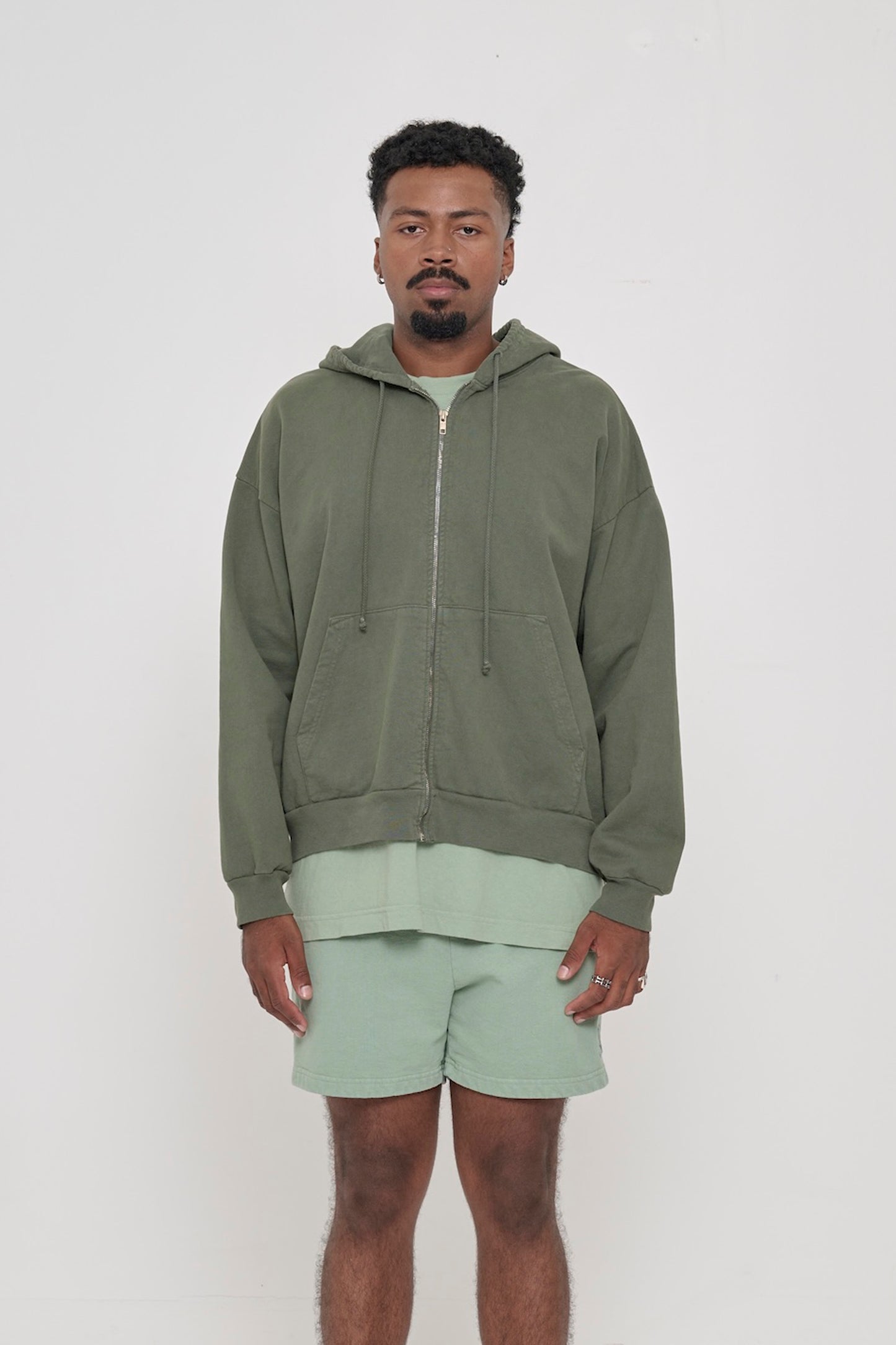 Front view of a person wearing Pine Trash Zip Up Hoodie. Hem hits mid hip.