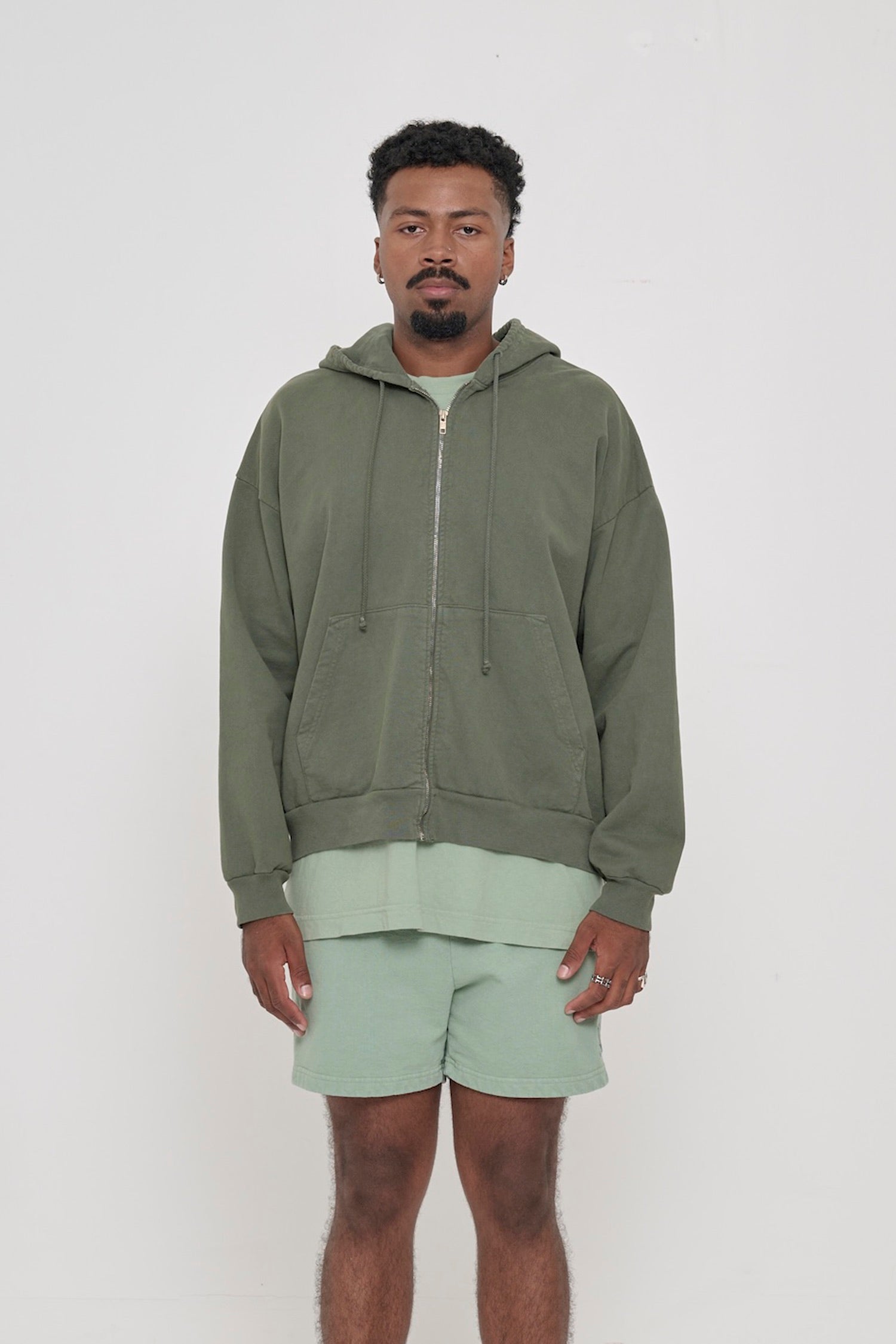 Front view of a person wearing Pine Trash Zip Up Hoodie. Hem hits mid hip.