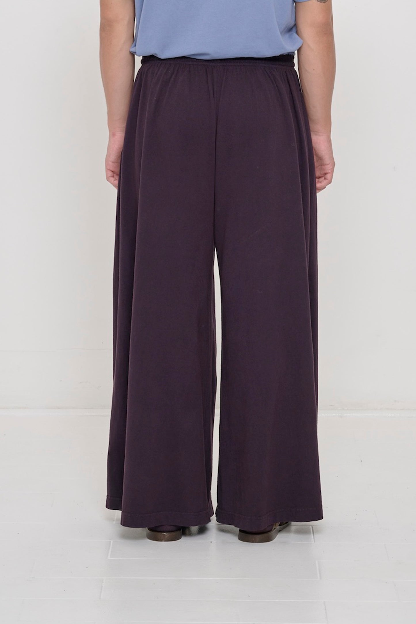 Back view of a person wearing Mulberry Tubular Pants showing flowing vertical fabric folds.