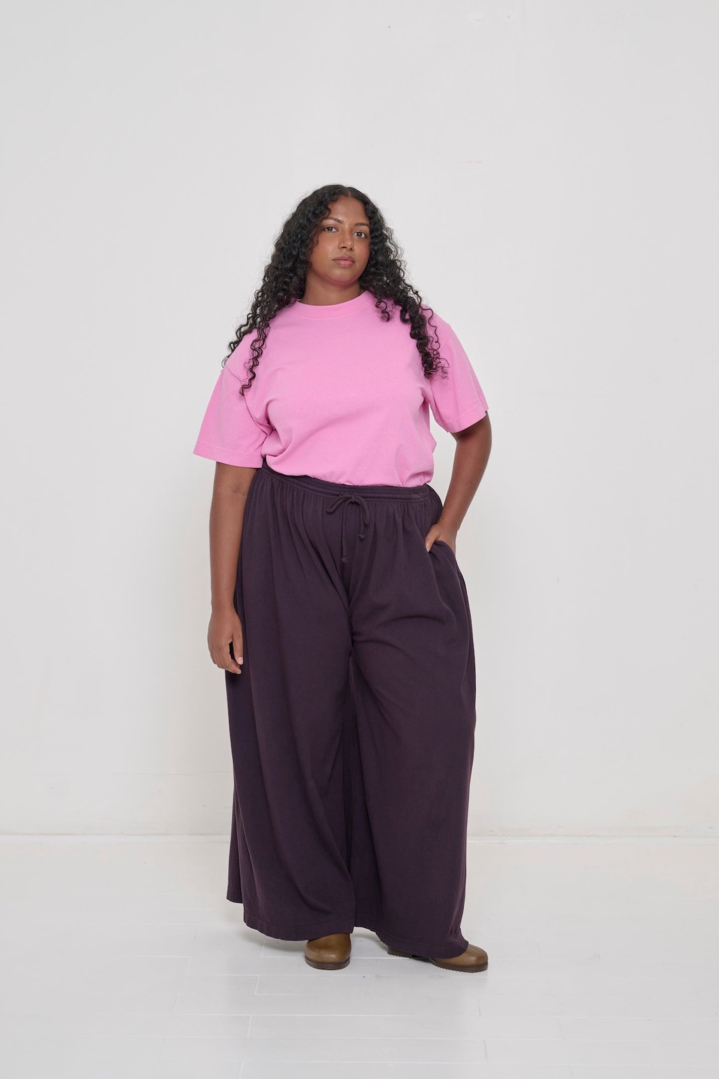 A person wearing Mulberry Tubular Pants with one hand in their pocket and Pixie Boxier Trash Tee tucked in.