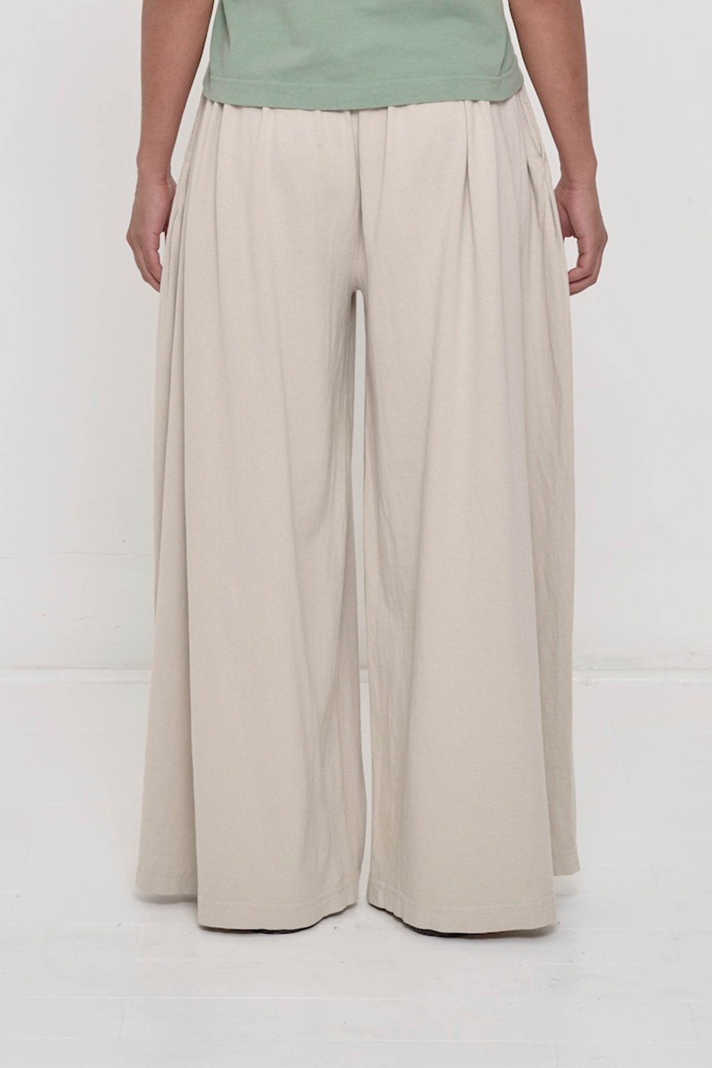 Back view of a person wearing Oat Tubular Pants showing flowing vertical fabric folds.