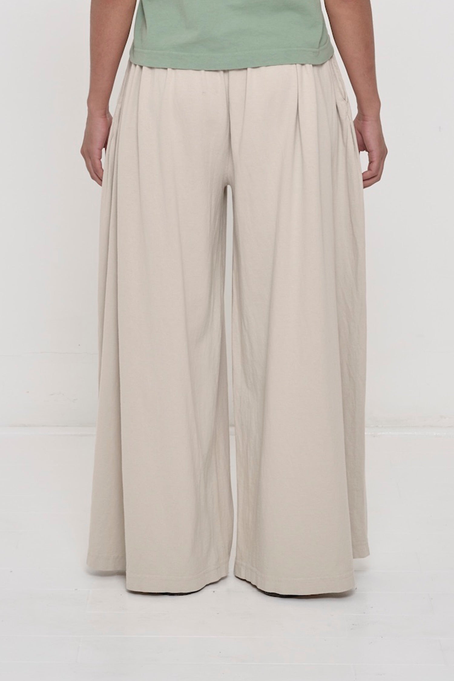 Back view of a person wearing Oat Tubular Pants showing flowing vertical fabric folds.
