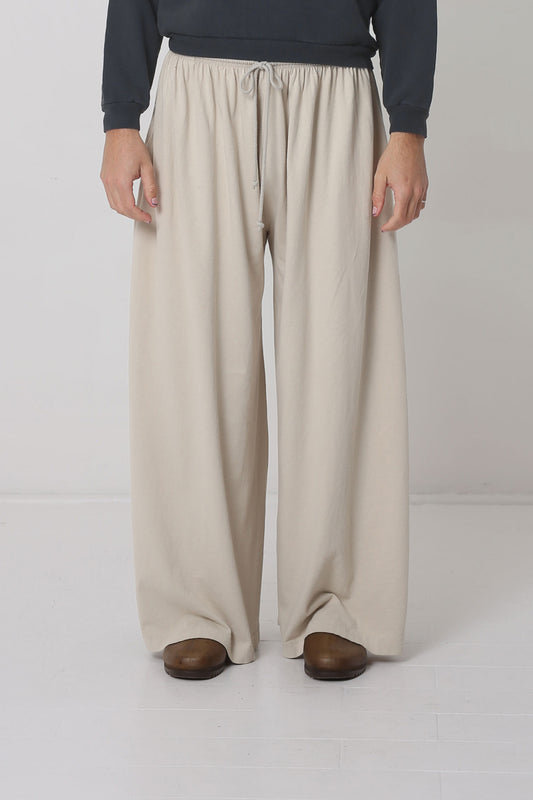 Waist-down front view of a 6' person in Oat Tubular Pants. Hem at bottom of heels.