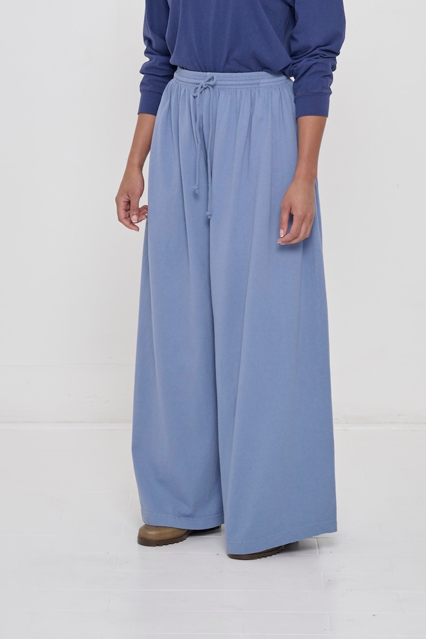 Person facing 45-degrees to the front in Periwinkle Tubular Pants, showing lack of side seams and flowing pant legs.