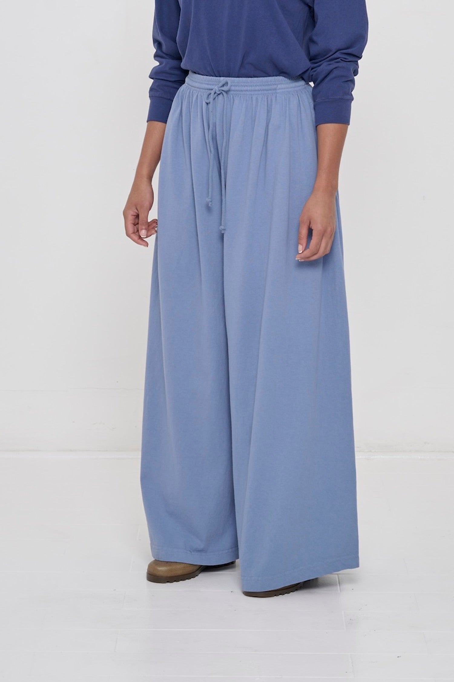 Person facing 45-degrees to the front in Periwinkle Tubular Pants, showing lack of side seams and flowing pant legs.