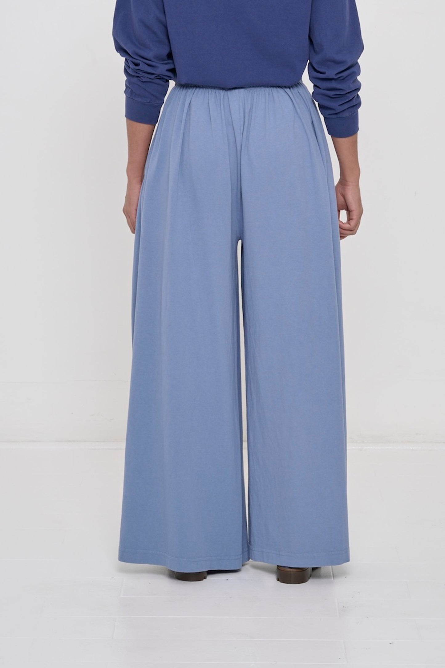 Back view of a person wearing Periwinkle Tubular Pants showing flowing vertical fabric folds.