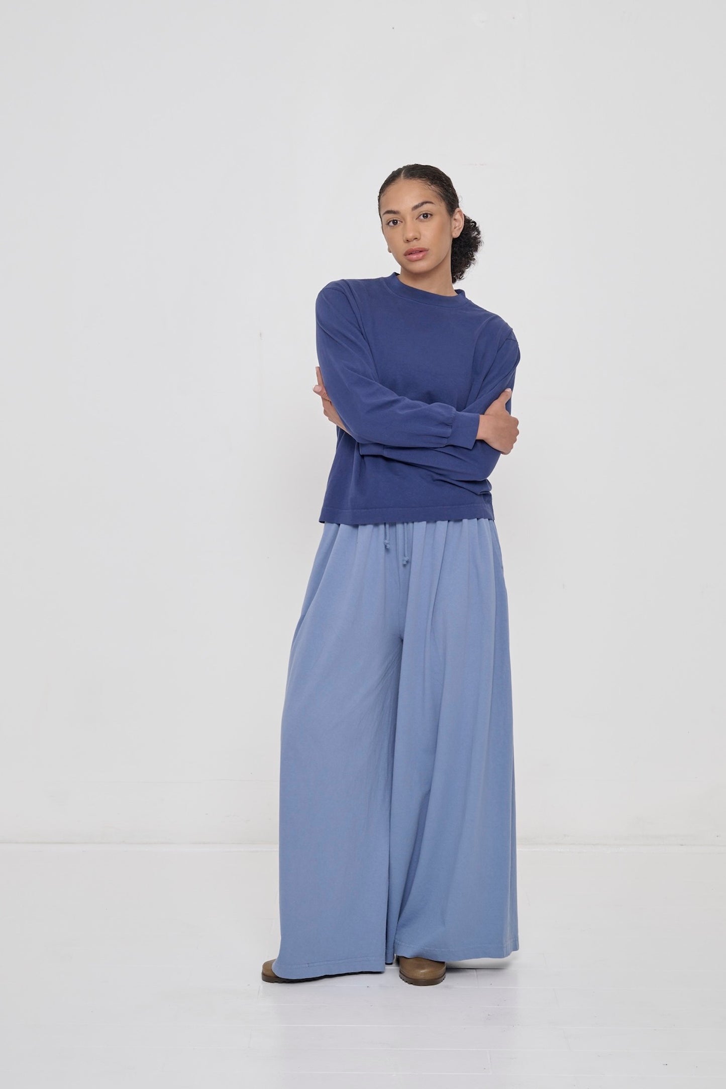 A person wearing Periwinkle Tubular Pants and a Washed Navy Long Sleeve Boxier Trash Tee. 