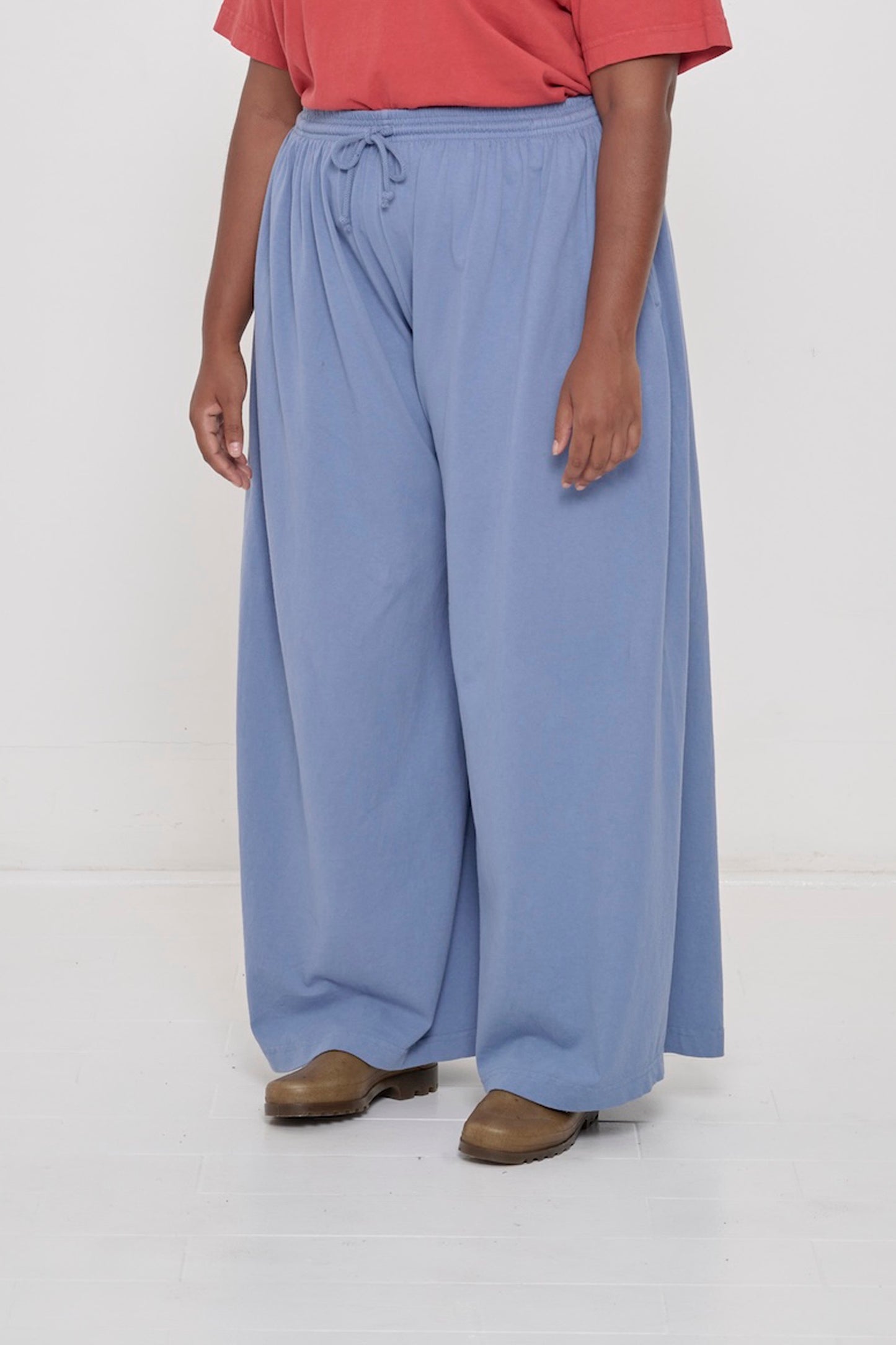 Person facing 45-degrees to the front in Periwinkle Tubular Pants, showing lack of side seams and flowing wide pant legs.