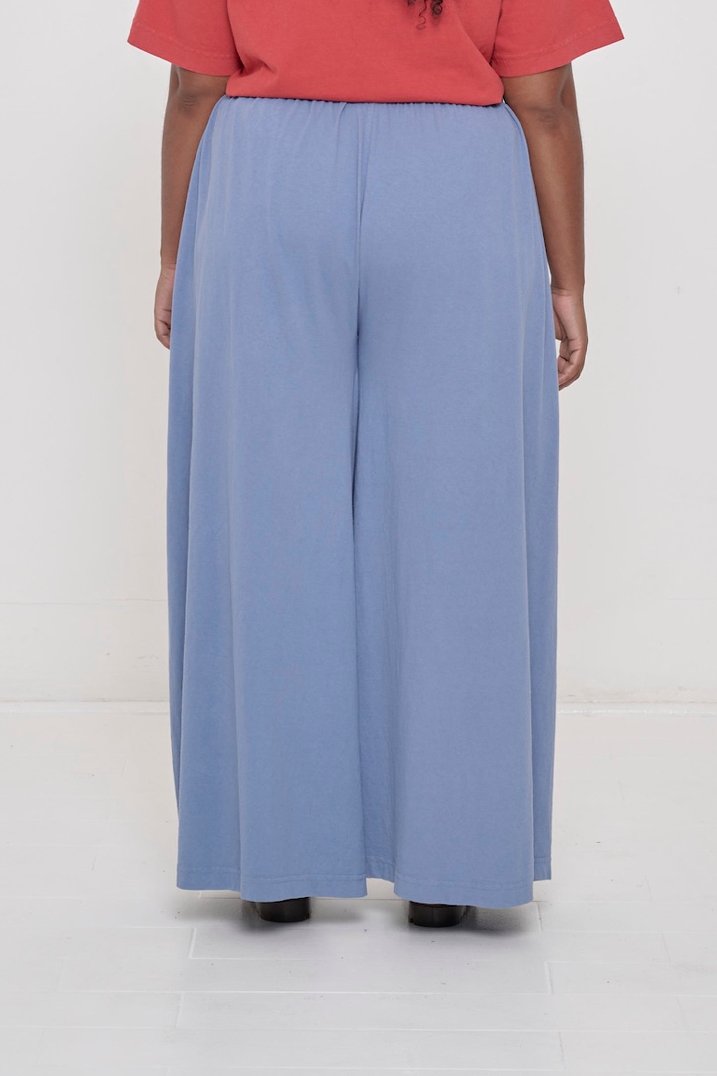 Back view of a person wearing Periwinkle Tubular Pants showing flowing vertical fabric folds.