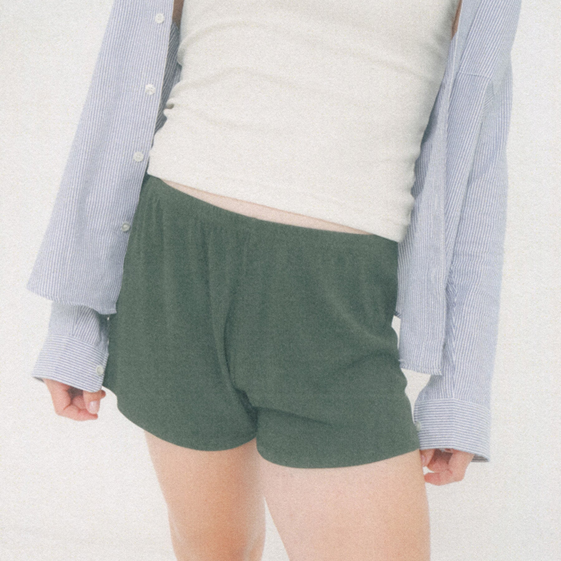 Cropped image of a person's torso, they are wearing the Stripe Poplin Button-Up Shirt with the Rib Tank in White and the Rib Shorts in Pine.