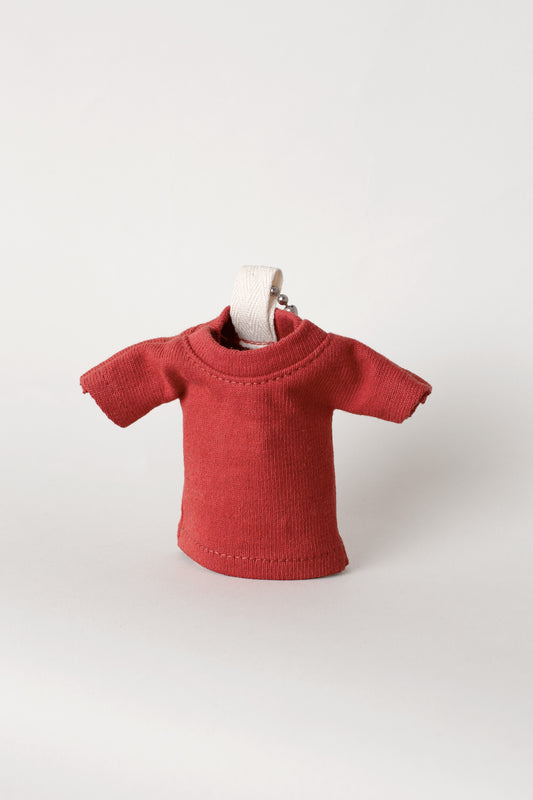 Red t-shirt keychain, propped up, against a light gray background