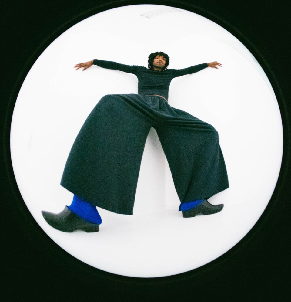 A person wearing a Slate Rib Long Sleeve and matching Tubular Pants, posed inside a large circular frame against a white background.